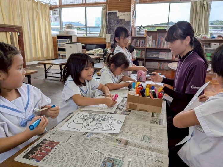 こどもたちが支援員と机を囲んで、ぬり絵をしている様子